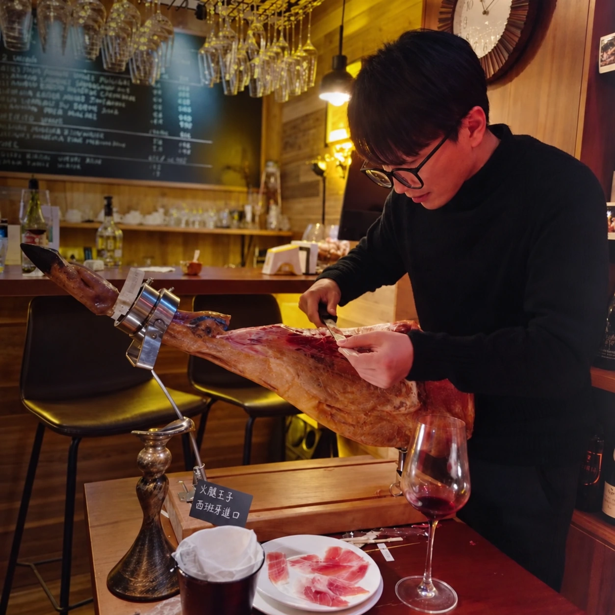 Fresh slices of ham being prepared beside a glass of wine