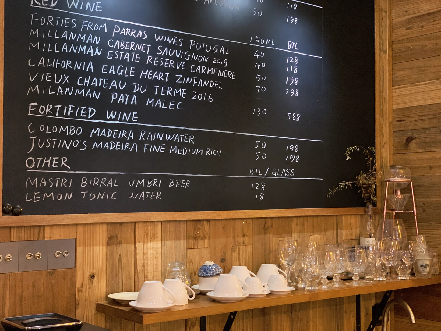 Wine chalkboard and glasses against a wooden wall